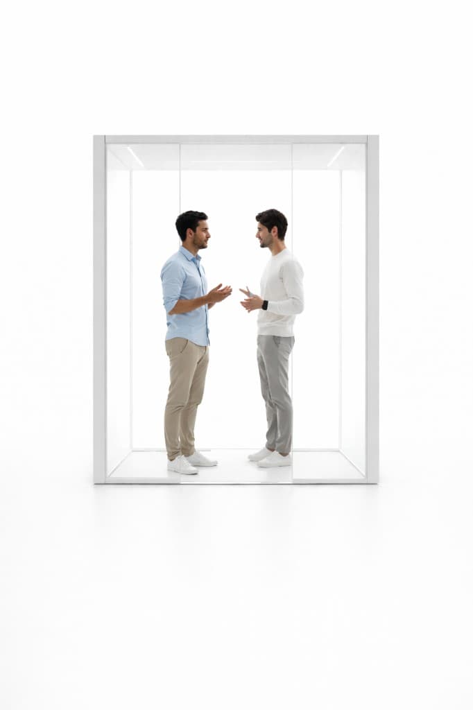 Two men standing in a wide clear glass booth